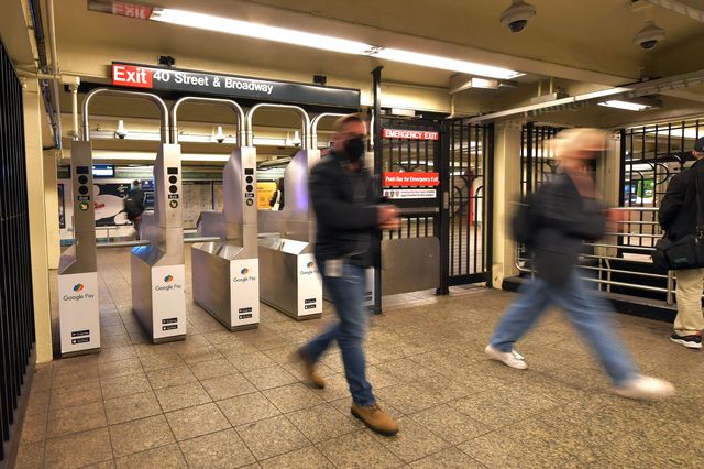 People walking through a subway turnstile